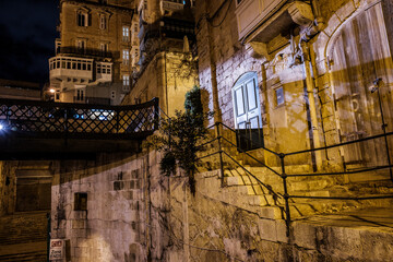 the empty streets of Valletta at night. Street lights illuminate the old houses