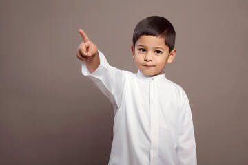 A young boy in a white religious outfit pointing upwards Fictional Character Created By Generative AI.
