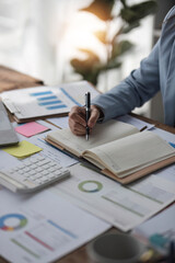businesswoman hand writing on notebook with pen while sitting at the table in modern office.