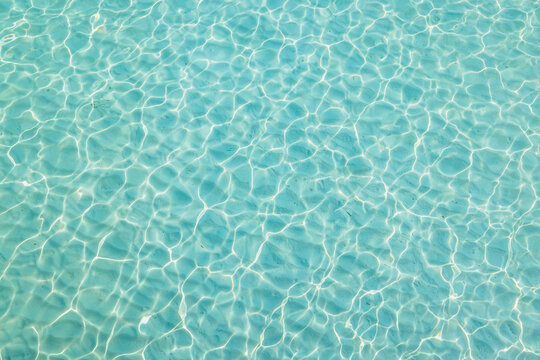 Water in swimming pool. Bright rippled water surface detail background. Tranquil tropical Mediterranean sea ocean shiny waves, sunlight pattern