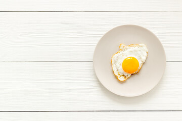 One fried egg on plate, top view. Breakfast background
