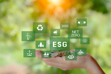 green energy concept. esg icon on pile of gold coins in hand on green nature background. Investing in the environment, society, governance, invest ESG in the industrial. ecology energy renewable.