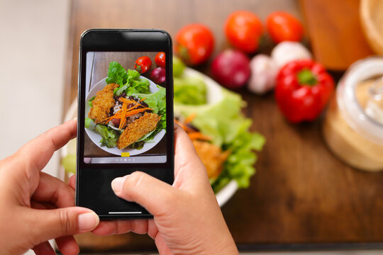 A man uses a black smartphone to take a picture of the food placed on the table. Food concept.