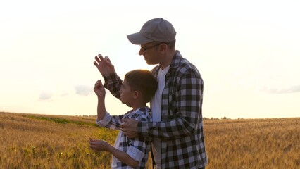 Family outdoor. Farmers at sunset. Father and son in a wheat field. The farmer's father teaches the child agronomy. agricultural industry. training teamwork
