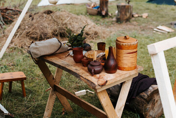 Medieval life, earthenware rustic ancient dishes on a wooden table in the forest