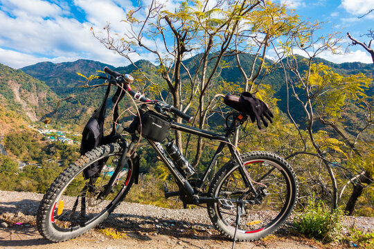 Mountain bike with luggage amidst picturesque natural surroundings, blue skies, and mountain landscapes in Dehradun City, Uttarakhand.