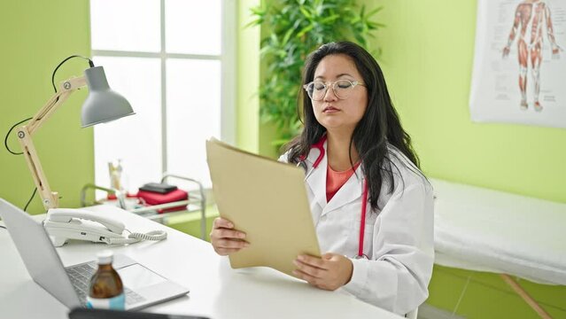 Young chinese woman doctor reading medical report at the clinic