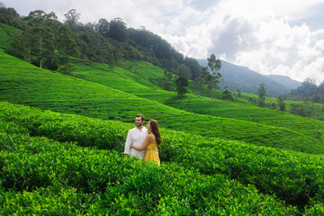 Nature's background tea plantations landscape with a romantic couple of travelers in love standing against embracing and looking away