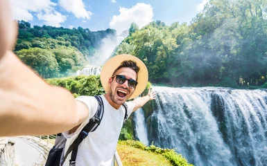 Photo sur Plexiglas Canada Handsome tourist visiting national park taking selfie picture in front of waterfall - Traveling life style concept with happy man wearing hat and sunglasses enjoying freedom in the nature