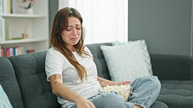 Young beautiful hispanic woman watching drama movie crying at home