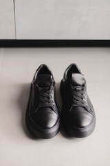 Close up details of black sneakers on the floor. Casual fashion style minimalistic shoes.