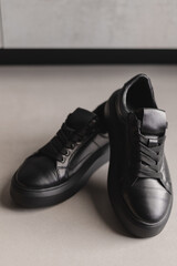 Close up details of black sneakers on the floor. Casual fashion style minimalistic shoes.