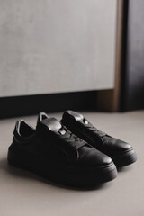 Close up details of black sneakers on the floor. Casual fashion style minimalistic shoes.