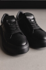 Close up details of black sneakers on the floor. Casual fashion style minimalistic shoes.