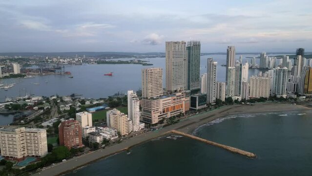 Aerial along the Playa De Bocagrande beaches and skyscrapers at dusk in Cartagena, Boliviar, Colombia. Drone truck right shot
