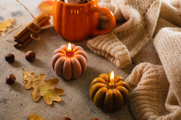 Burning candles shape of pumpking, mug with aiutumn drink, leaves and cinnamon. Autumn mood, hygge atmosphere. - 631077743