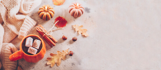 Autumn still life. Cocoa mug and marshmallow, pumpkin candles, knitted sweater, cinnamon sticks and autumn leaves. Top view, flat lay. Banner for web site - 631077989
