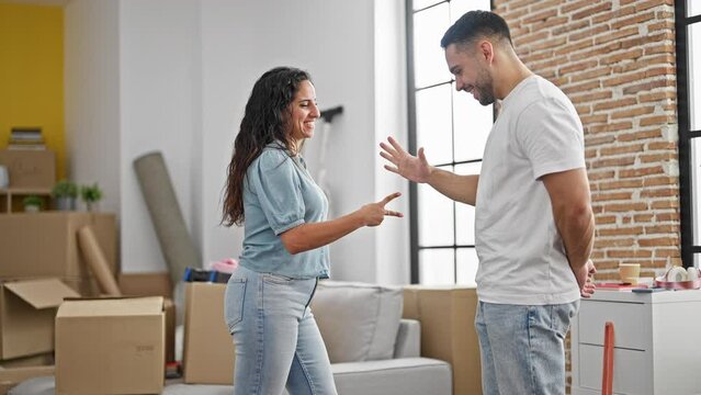 Man and woman couple playing rock scissors paper game smiling at new home