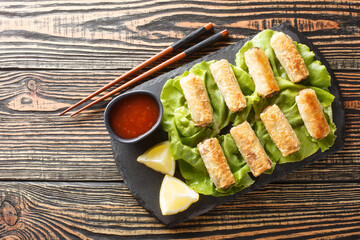 Vietnamese nem fried spring rolls with chicken and vegetables served with sauce close-up in a plate on the table. Horizontal top view from above