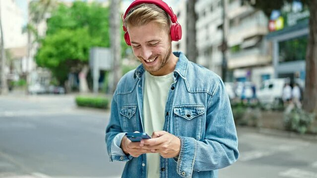 Young caucasian man using smartphone wearing headphones at street