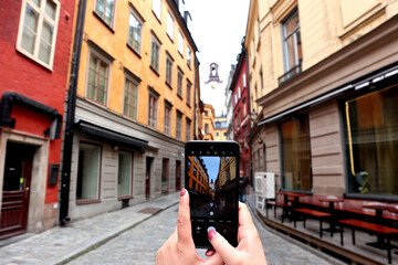 A street in downtown Stockholm, Sweden with the steeple of St. Nicholas Church in the background. Photographed through a cell phone camera of a tourist
