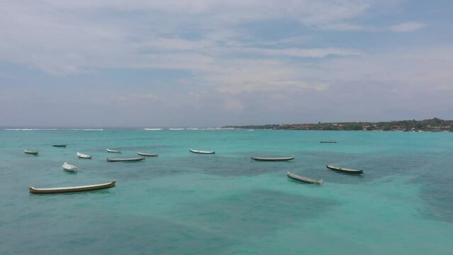 Drone flying over fishing boats in Nus Ceningan island. Seaweed farmers boats in Nusa Ceningan and Nusa Lembongan. Aerial shot of Balis Nusa Islands. Drone flying close above  tropical turquoise water
