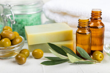 Spa olive. Composition with a jar of natural olive cream, essential oils, sea salt and natural handmade soap with olive and olive sprigs on a white background. Beauty and relax concept. Flat lay