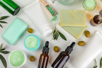 Spa olive. Composition with a jar of natural olive cream, essential oils, sea salt and natural handmade soap with olive and olive sprigs on a white background. Beauty and relax concept. Flat lay