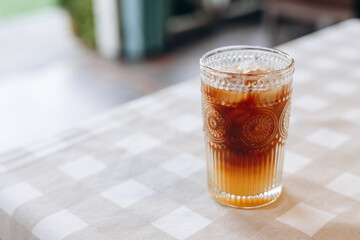A mix of orange juice, coffee and ice in a decorative glass standing on a beige checkered...
