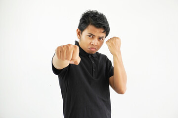 young asian man against a white studio background, throwing a punch, anger, fighting due to an argument, boxing, wearing black polo t shirt.