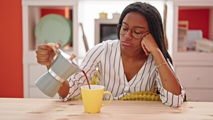 African american woman pouring coffee on cup sitting on table tired at dinning room