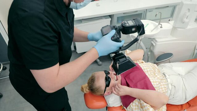 A dentist takes a picture of a patient's teeth. A doctor photographer captures his work with the help of photography. Photo report in dentistry.