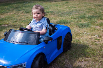 Baby fährt mit Kinderauto durch Garten