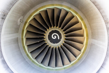 Close up of jet engine with yellow glow and spinner, sensor and fan blades visible inside of the cowling.