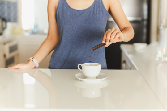Woman hand pouring instant coffee sachet into a cup.