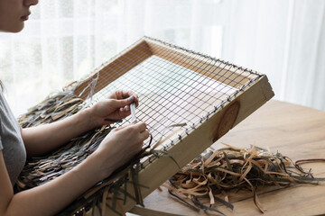 Woman weaving camouflage military mesh for helmet.
