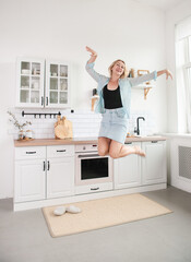 Fototapeta na wymiar Cheerful woman jumping and dancing in the kitchen