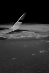 Black and white photo of a plane above the cloud
