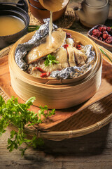 asian traditional double boiled herbal kampong chicken hot healthy soup in bamboo basket on vintage wood table ingredient background Chinese halal food banquet menu for restaurant