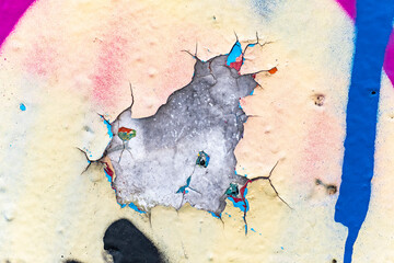 Close up of the colorful cracks and chips of an old wall.