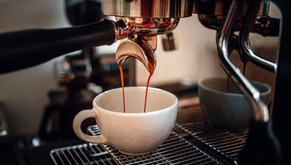 Close-up of espresso pouring from the coffee machine into a coffee cup. Professional coffee brewing