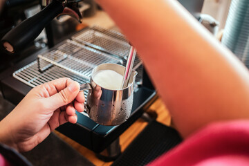 Professional barista warming milk for cappuccino. hand of Barista using the coffee machine for coffee latte