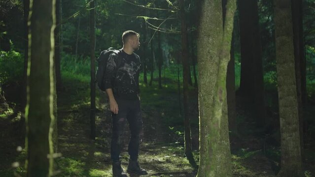 A person hiking or camping outdoors is walking along a trail. Outdoor lifestyle. The man got lost in the forest. green forest at high altitude. View of an active healthy man with a backpack on a walk.