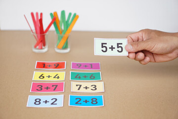 Close up teacher hand hold paper cards with numbers  addition, plus for teaching Math subject. Concept, Education, Teaching aid, materials for kids. Education, Practice calculate             