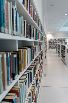 A large number of bookshelves with books. White bookshelves in the library, on which there are many books.