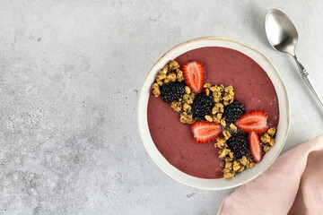 Obraz na płótnie Canvas Smoothie bowl with strawberries, blackberries and granola on a gray background. Healthy breakfast. Top view. Copy space.