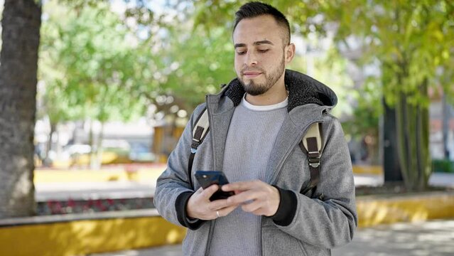 Hispanic man smiling confident taking picture with smartphone at the park