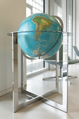 A large globe in the interior. A large globe on a metal stand is in the room. South America on the...