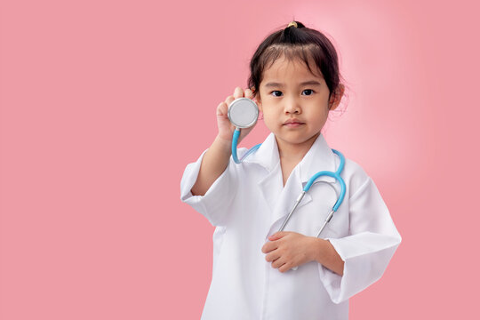 Asian girl holding a stethoscope Wearing a white medical gown on a pink background
