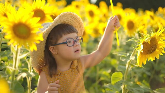 Raising a child with Down syndrome. A girl with down syndrome with a windmill in a field of sunflowers.